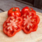 Tomatoes and a sliced tomato on a wooden cutting board