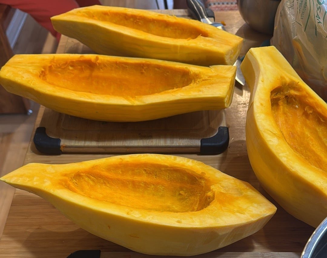 Sliced yellow squash on a wooden cutting board with a knife and other kitchen items.