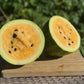 Halved watermelon on a wooden board with a blurred green background