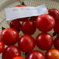 Bowl of red tomatoes with a piece of paper on a mesh surface