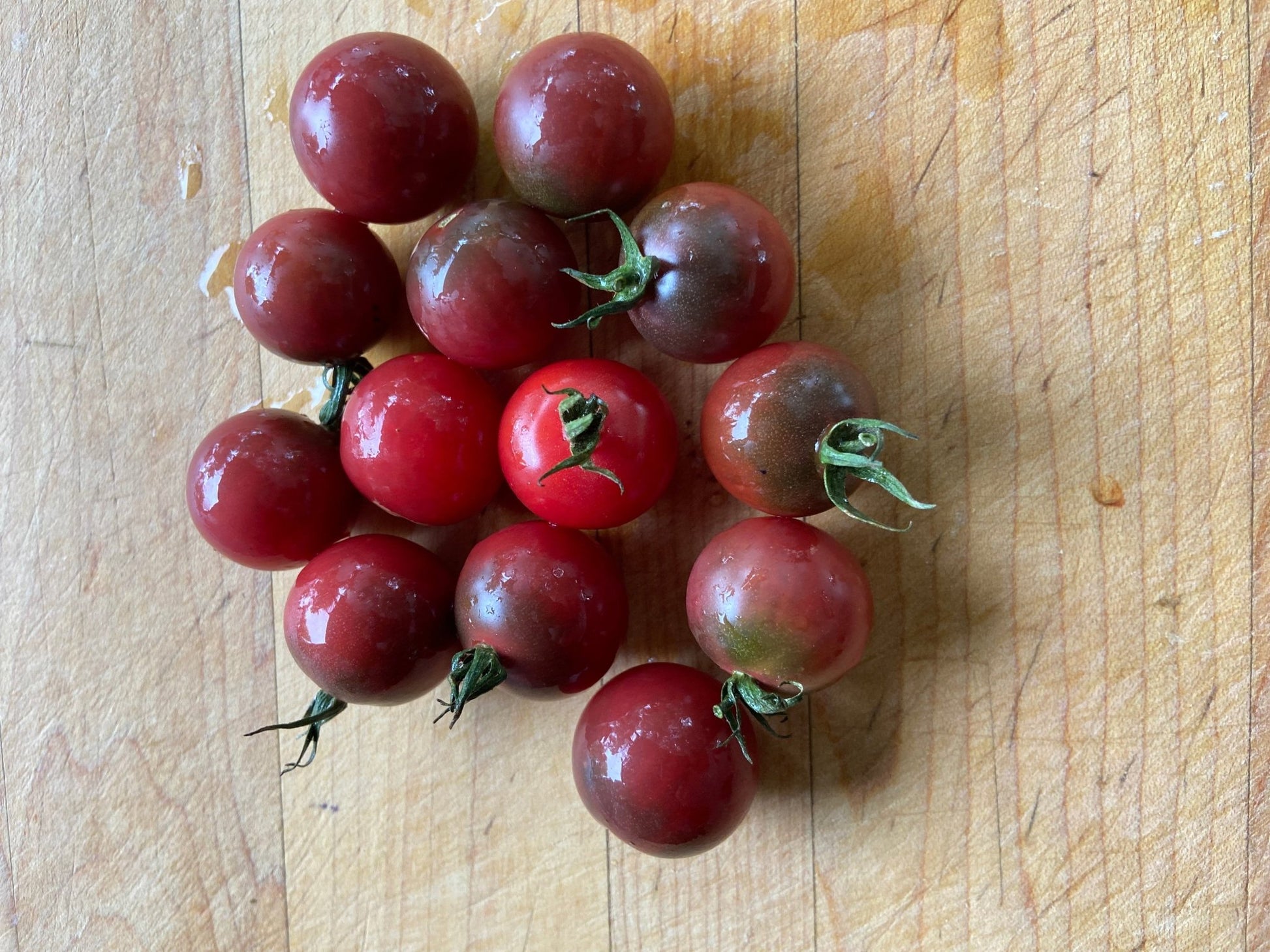 Cluster of red and purple tomatoes on a wooden surface